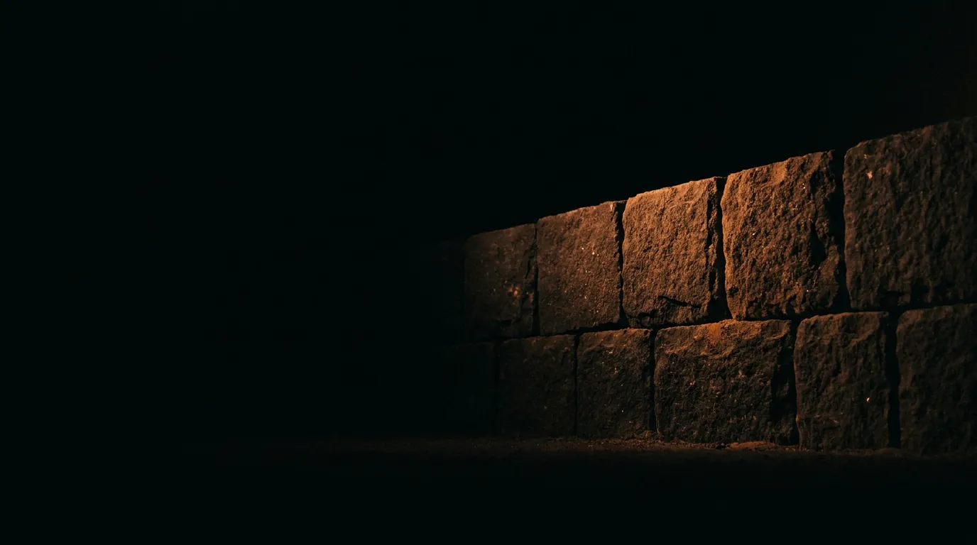 Muro de piedra iluminado con luz naranja en la oscuridad